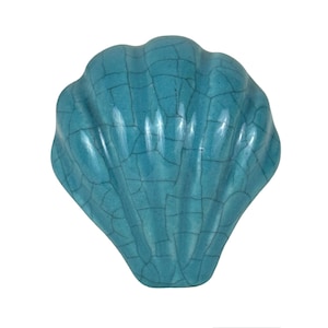 May include: A teal blue ceramic seashell with a crackled glaze finish. The seashell is a decorative object.