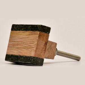 May include: A square wooden knob with a green marble inlay and a metal screw. The knob is attached to a metal screw.