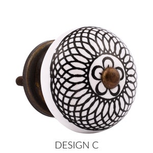 May include: White ceramic knob with a black and white geometric design. The knob has a brass base and a screw for attaching it to a drawer or door. DESIGN C.