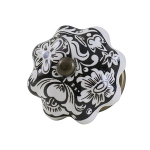 May include: Black and white ceramic cabinet knob with a floral design. The knob has a brass screw.