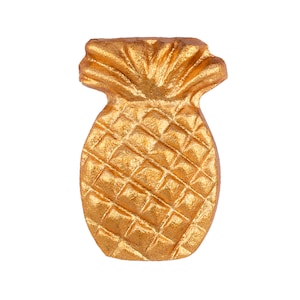 May include: A gold pineapple shaped decorative object. The pineapple has a detailed textured surface.