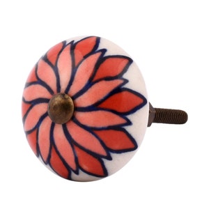 May include: A decorative ceramic cabinet knob with a floral design. The knob features a white base with a red and pink flower pattern outlined in dark blue. It has a brass-colored center and a threaded metal screw for attachment.