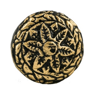 May include: A round, black and gold decorative knob with a floral design. The knob has a raised, textured surface with a central flower motif.