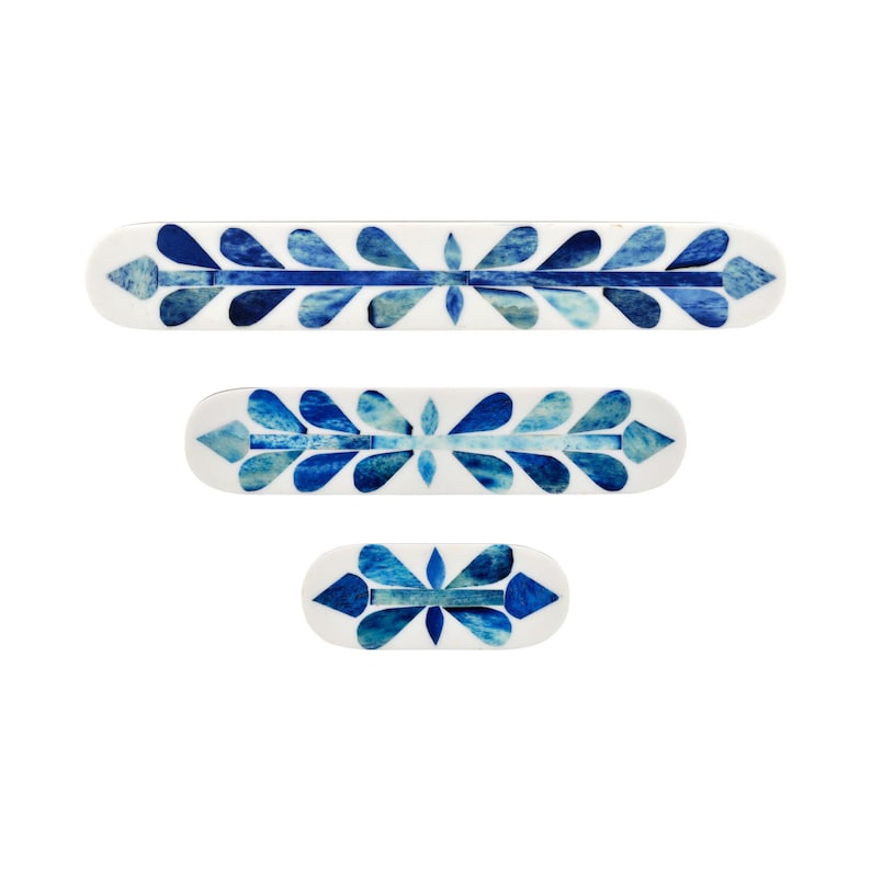 May include: Three elongated, rounded rectangular trays of varying sizes, each featuring a white base with a central horizontal line and symmetrical, petal-like blue and light blue decorative inlays arranged in a repeating leaf-like pattern.