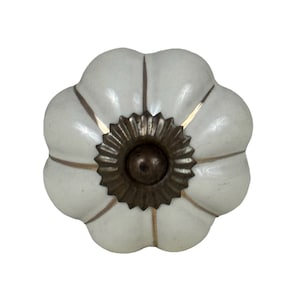 May include: White ceramic pumpkin-shaped cabinet knob with a gold trim and a bronze center.