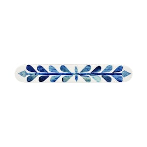 May include: A long, rectangular decorative bar featuring a white base with a central horizontal line and symmetrical, leaf-shaped patterns in various shades of blue, ranging from light sky blue to deep navy, arranged along the entire length.