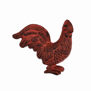 May include: A red and black rooster figurine. The rooster is made of metal and has a textured surface. The rooster has a detailed design, with feathers and a comb. The figurine is a decorative item.