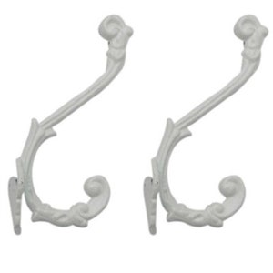 May include: Two white metal hooks with a decorative floral design. The hooks are curved and have a pointed end.