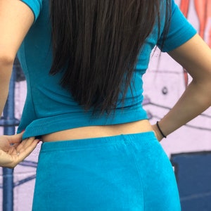 May include: A woman wearing a turquoise blue short-sleeved shirt and matching pants.