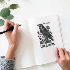 May include: A black and white illustration of a raven perched on a skull with roses. The text "Ex Libris" and "Caleb Stormrider" are below the illustration.