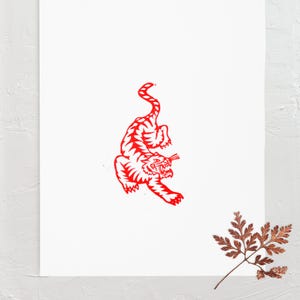 Puede incluir: Impresión de arte de línea roja de un tigre sobre un fondo blanco.