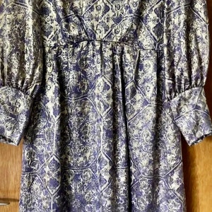 May include: A long-sleeved dress with a blue and white geometric pattern. The dress has a fitted bodice and a flowing skirt.