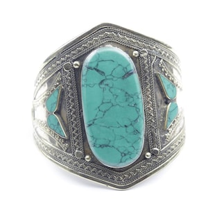 May include: A silver bracelet with a turquoise stone and intricate designs.