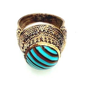 May include: A gold-toned ring with an oval, striped turquoise and brown stone. The ring band has a textured, ornate design. The stone is the focal point, with its vibrant colors and unique pattern.