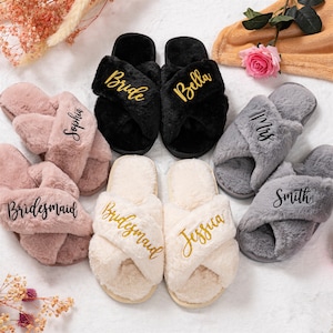 Könnte beinhalten: Verschiedene Plüsch-Cross-Band-Hausschuhe in Rosa, Schwarz, Creme und Grau. Jedes Paar hat gestickte Texte, darunter "Bride", "Bella", "Mrs.", "Smith", "Bridesmaid", "Sophia" und "Jessica". Die Hausschuhe sind für Komfort konzipiert.