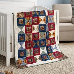 May include: A patchwork quilt featuring a repeating pattern of square blocks in deep red, navy blue, and cream. The design incorporates alternating solid-colored squares and intricate geometric triangles, finished with a thin grey border trim.