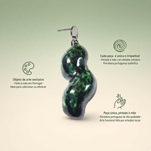 Könnte beinhalten: Ein einzelner Ohrring mit einem unregelmäßig geformten, organischen Porzellananhänger in glänzendem, dunkelgrün-schwarz marmoriertem Design. Der Anhänger hängt an einem kleinen silberfarbenen Metallstecker. Text auf dem Bild in Portugiesisch.