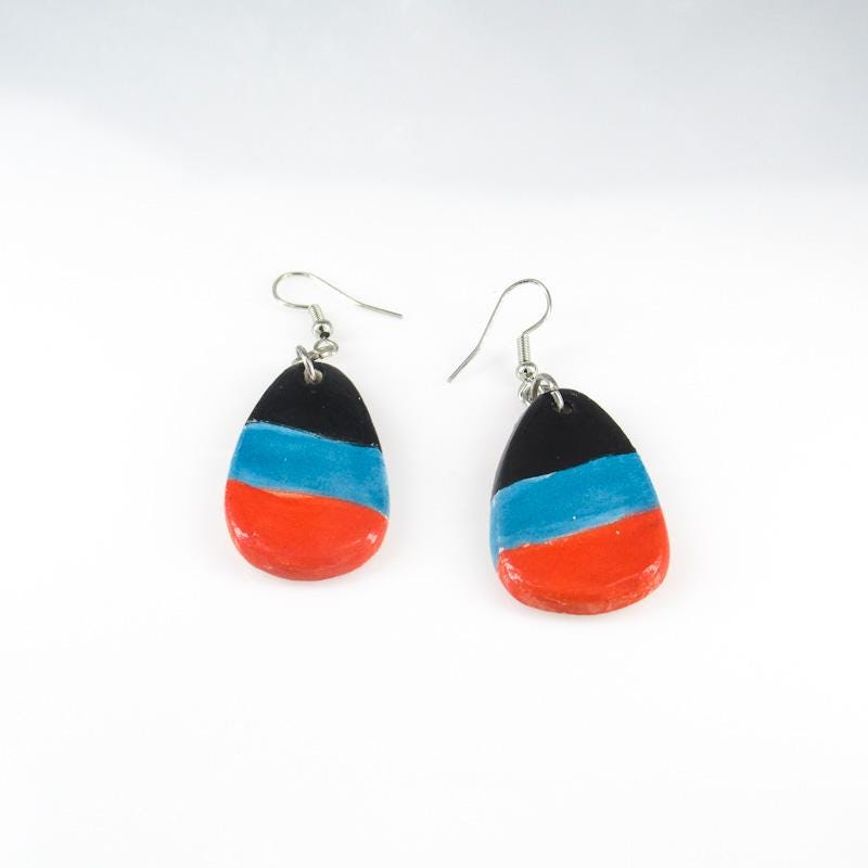 Tricolor Teardrop – Vibrant ceramic earrings with a striking design featuring black, blue, and red bands in a teardrop shape.
