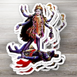 May include: A sticker sheet featuring multiple stickers of the Hindu goddess Kali. The stickers depict Kali with multiple arms, standing on a figure, and holding various objects. The stickers are in shades of purple, gold, and red.