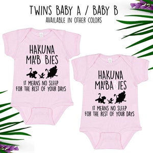 May include: Two pink baby onesies with short sleeves and the text "Hakuna Ma'Babies" and "It means no sleep for the rest of your days". The onesies feature a silhouette of Simba, Timon, and Pumbaa from the Disney movie The Lion King.