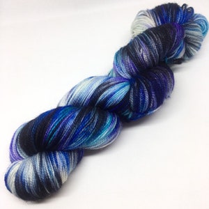 K&ouml;nnte beinhalten: Eine Garnrolle mit einem blauen, wei&szlig;en und schwarzen Farbmuster. Das Garn ist weich und flauschig und perfekt zum Stricken oder H&auml;keln.