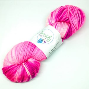 May include: A skein of pink, white and purple yarn with a white label that reads "Twinkly Knits" and "75% Merino Wool 25% Nylon".