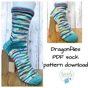 May include: A pair of teal blue and multi-colored striped socks with a dragonfly design. The socks have a pink band at the top. The image includes the text "Dragonflies PDF sock pattern download" and a logo for "Twinkly Knits".