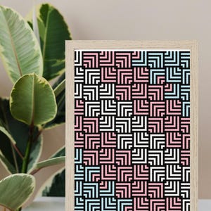 May include: A framed geometric print with a black background and a pattern of white, pink, and blue squares. The print is in a light wood frame.