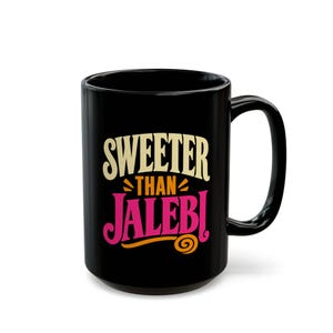 Könnte beinhalten: Ein schwarzer Keramikbecher mit dem aufgedruckten Text SWEETER THAN JALEBI auf der Vorderseite. Das Wort SWEETER ist cremefarben, THAN ist orange und JALEBI ist pink mit einem orangefarbenen Wirbelakzent am unteren Ende des Buchstabens I.