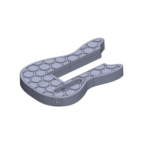 Pu&ograve; includere: Un oggetto grigio a forma di U con un motivo a nido d'ape sulla sua superficie. L'oggetto ha una base rettangolare e due estremit&agrave; curve. Sembra essere fatto di un materiale solido, possibilmente plastica o metallo.