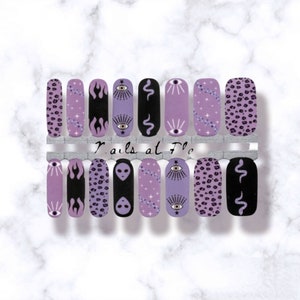 May include: A set of 12 purple and black nail wraps with various designs, including flames, eyes, snakes, aliens, and leopard print. The nail wraps are arranged on a white background with the text "Nails at The" visible in the center.