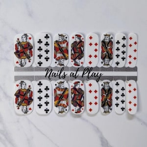 May include: A sheet of nail wraps with a playing card theme. The wraps feature images of the King of Hearts, King of Diamonds, King of Clubs, and King of Spades. The text "Nails at Play" is printed on the sheet.