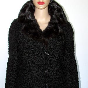 May include: A black fur coat with a large, black fur collar. The coat has a button closure and is made of a curly fur.