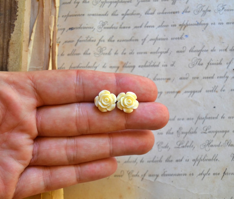 Puede incluir: Un par de peque&ntilde;os pendientes de cer&aacute;mica blanca en forma de rosa. Las rosas est&aacute;n detalladas con p&eacute;talos delicados y son un dise&ntilde;o cl&aacute;sico y elegante.