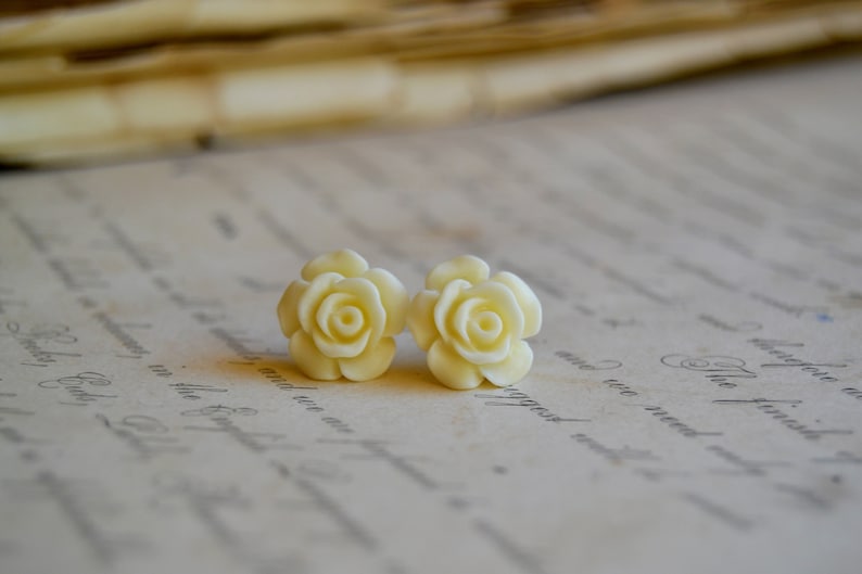 Puede incluir: Un par de pendientes de color blanco con forma de rosa. Los pendientes est&aacute;n hechos de un material liso y blanco y tienen un dise&ntilde;o delicado y femenino.