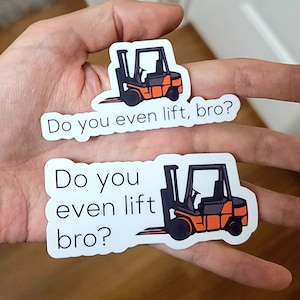 Könnte beinhalten: Zwei Aufkleber mit einem Cartoon-Gabelstapler in Schwarz und Orange. Die Aufkleber tragen den Text "Do you even lift, bro?" in schwarzer Schrift. Die Aufkleber sind weiß mit abgerundeten Kanten.