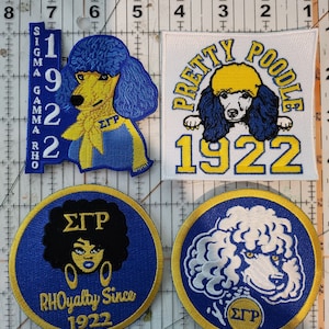 May include: Four embroidered patches with a blue and gold color scheme. The patches feature a poodle, the letters "Sigma Gamma Rho", and the year "1922".