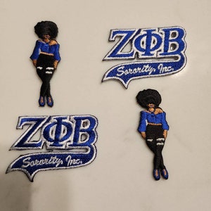 Puede incluir: Dos parches bordados azules y blancos con el texto "ZOB Sorority Inc." y dos parches bordados azules y negros de una mujer con una blusa azul y pantalones negros.