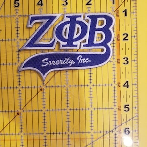May include: A blue and white embroidered patch with the letters "ZΦΒ" and the text "Sorority, Inc."