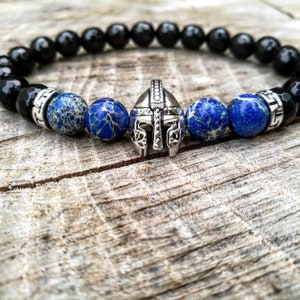 May include: A black onyx and blue jasper beaded bracelet with a silver gladiator helmet charm.