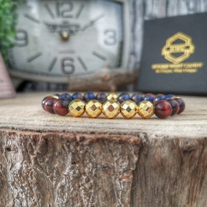 May include: A beaded bracelet with gold, red, and blue beads. The bracelet is made of natural stones and is a stylish accessory.