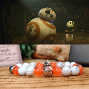 Op de afbeelding: Een armband met witte en oranje kralen met een zilveren bedel van de droid BB-8 uit Star Wars.