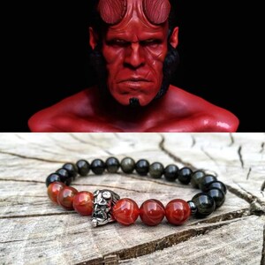 Op de afbeelding: Een rode en zwarte kralen armband met een zilveren bedel van een demonenkop. De kralen zijn gemaakt van carneol en zwarte obsidiaan.