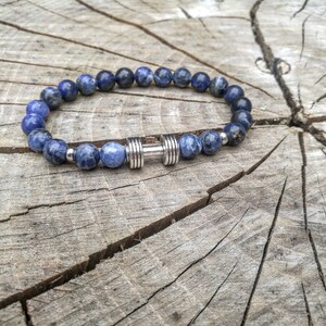 May include: A blue gemstone beaded bracelet with a silver dumbbell charm.