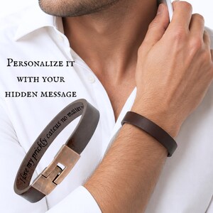 May include: A dark brown leather bracelet with a metallic clasp. The interior of the leather band features the engraved text "I love my prickly catcus no matter". The text "PERSONALIZE IT WITH YOUR HIDDEN MESSAGE" is visible in the image.