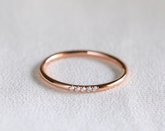 May include: A delicate rose gold band ring with a row of five small diamonds.