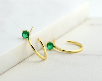 May include: A pair of gold hoop earrings with a single green gemstone on each hoop.