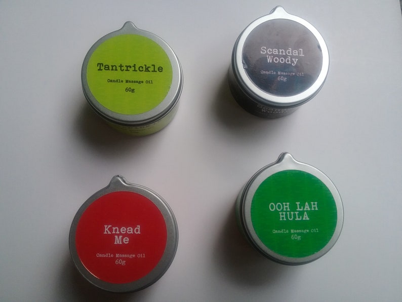 Puede incluir: Cuatro peque&ntilde;as latas redondas de metal con tapas de colores y etiquetas blancas. Las etiquetas tienen diferentes nombres y descripciones para aceite de masaje de vela. Los nombres son "Tantrickle", "Scandal Woody", "Knead Me" y "Ooh Lah Hula". Cada lata contiene 60 g de aceite de masaje de vela.