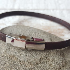 May include: A brown leather bracelet with a silver clasp.