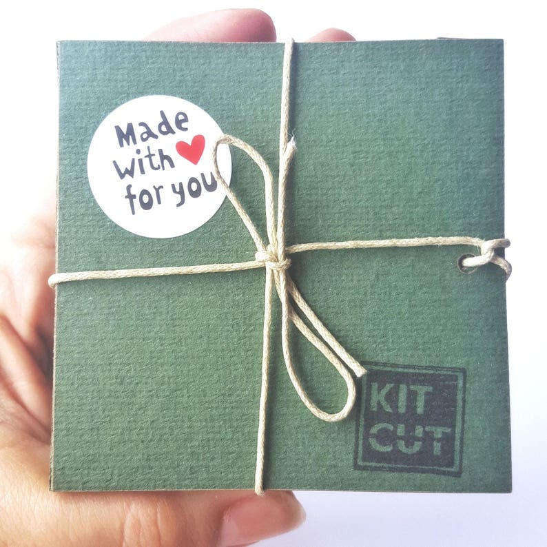 May include: A green gift box tied with twine and a white sticker that says "Made with love for you". The box has a black stamp that says "Kit Cut".